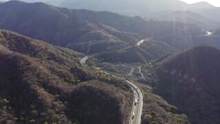 Flying over a rugged landscape with a w highway traversing the mountains at dusk