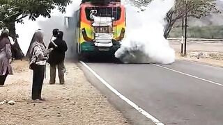 A bus emits smoke while carrying passengers on the streets of Indonesia