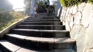 A cat sleeping in the middle of the stairs slowly turns over when it sees someone approaching.