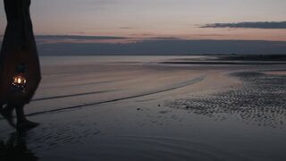 Woman walking on beach with lantern